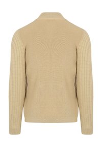 Beige trui met geribbelde textuur en gladde zijkanten. Voorzien van een hoge kraag en aansluitende manchetten, wat zorgt voor een gestructureerde silhouet.