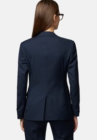 Granatowa marynarka o dopasowanym kroju, z wykładanymi klapami i pojedynczym wentylem. Posiada zapinane mankiety oraz elegancki, minimalistyczny design.