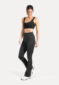 Zwarte atletische cropped top en uitlopende legging van gladde, rekbare stof. Heeft een hoge taille en een eenvoudig ontwerp zonder patronen.