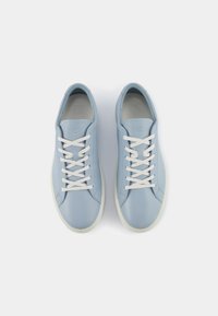Ljusblå lädersneakers med vita snörningar, rund tå och strukturerad yta. Har en minimalistisk design och en krämfärgad sula.