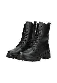 Bottes de combat en cuir noir avec de épaisses semelles en caoutchouc, des fermetures éclair sur le côté et des lacets noirs, présentées en vue latérale-antérieure sur un fond blanc.