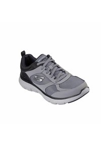 Scarpa sportiva grigia con tomaia in rete, dettagli neri e suola bianca. Presenta lacci e un tassello sul tallone per indossarla facilmente.