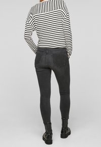 Černé skinny džíny vyrobené z denimu, s hladkou texturou a přiléhavým střihem. Nosit s černobílým pruhovaným topem.