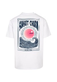 Camiseta blanca de manga corta con un gráfico frontal que presenta un sol estilizado rosa y olas, bordeado por la frase "SUNSET CHARM" en letras negritas.