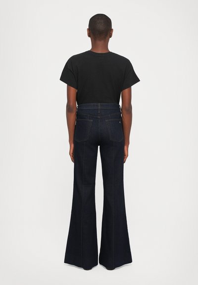Black t-shirt and high-waisted flared dark denim jeans. Jeans feature back pockets and a smooth texture, with a fitted waist and wide flares.