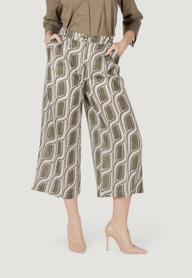 Pantaloni a gamba larga tagliati, con un motivo geometrico verde e bianco, realizzati in tessuto leggero. Presentano tasche laterali, vita alta e una texture liscia.