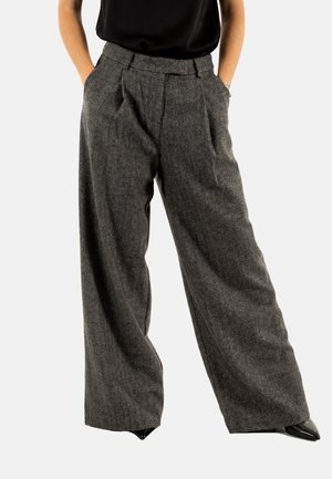 Wijde broek gemaakt van een gestructureerde grijze stof, met voorplooien, een hoge tailleband en zijzakken, gestyled met een zwarte top.