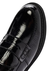Scarpa in pelle verniciata nera con punta arrotondata, superficie texturizzata, cinturino con fibbia in metallo e suola in gomma a profilo basso.
