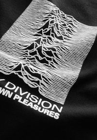 Sort stof t-shirt med et hvidt linjekunst-design af bjerge med vandrette striber og teksten "JOY DIVISION PLEASURES."