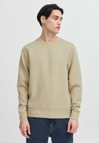 Lichtbeige sweatshirt met een ronde hals, ribgebreide manchetten en zoom. Zachte, gestructureerde stof; gedragen met donkerblauwe jeans. Eenvoudig en minimalistisch ontwerp.