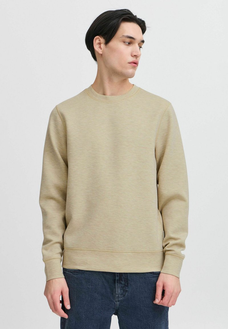 Lichtbeige sweatshirt met een ronde hals, ribgebreide manchetten en zoom. Zachte, gestructureerde stof; gedragen met donkerblauwe jeans. Eenvoudig en minimalistisch ontwerp.