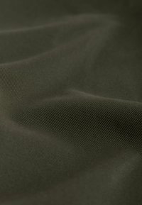Dark green fabric with a smooth texture and visible fine ribbing. The material appears soft and flexible, showing gentle folds and creases.