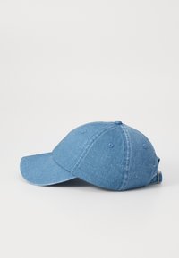 Világoskék farmer baseballsapka, ívelt csúccsal, hatpaneles kialakítással és állítható pánttal a hátsó részen. Textúrált anyag, finom színezett foltokkal.