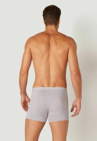 Boxeri din bumbac gri, cu un brâu elastic moale, prezentând un design ajustat și cusături minime, văzuți din spate.