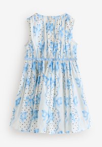 Biele šaty bez rukávov s modrými vzormi stužiek, čiernymi bodkami, gombíkmi na prednej strane a modrým pásom v páse.