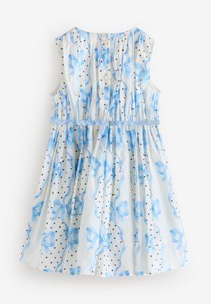 Ujjatlan fehér ruha kék szalagmintákkal, fekete pöttyökkel, gombokkal az elején és kék derékszalaggal.