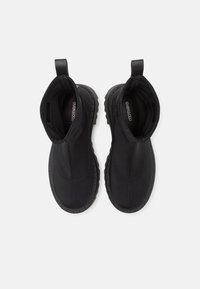 Černé kotníkové boty s hladkým syntetickým svrškem, elastickými bočními panely a texturovanou gumovou podrážkou. Mají minimální švy a poutka na zvedání.