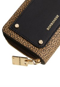 Black and brown patterned wallet with a gold zipper and hardware. Features a smooth leather patch with embossed brand name and accents.
