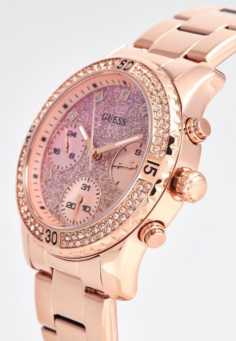 Reloj cronógrafo color oro rosa con una esfera rosa brillante, tres subesferas, acentos de cristales en el bisel y una correa de eslabones.