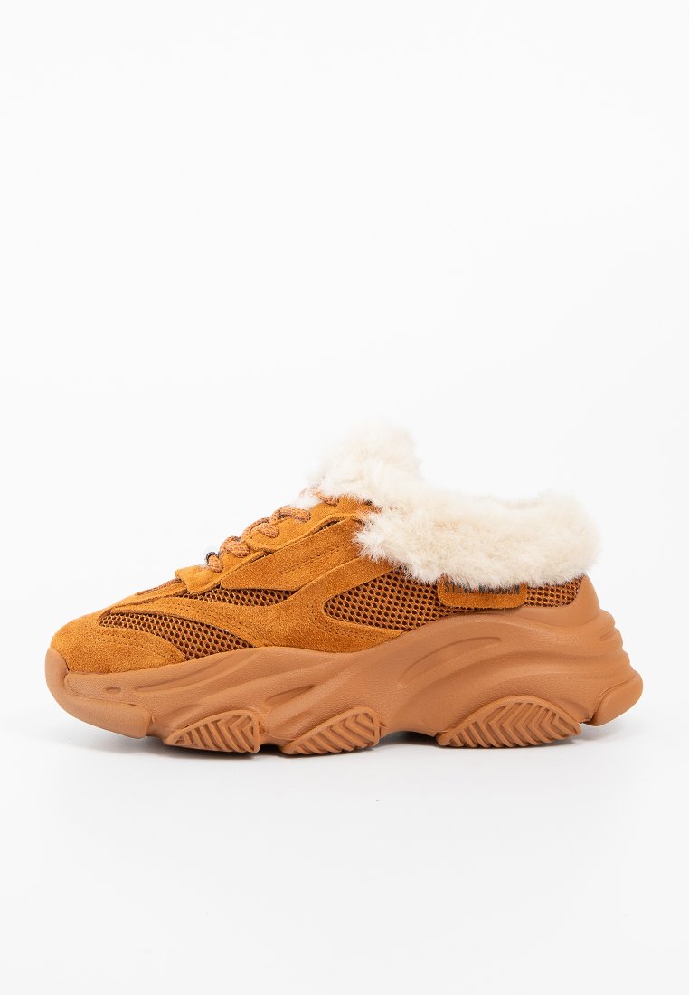 Sneaker in suede di colore arancio-marrone con un morbido colletto bianco, pannelli in rete e una robusta suola in gomma dotata di un motivo di aderenza testurizzato.