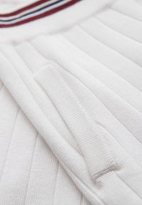 Tissu blanc côtelé avec une poche et une ceinture ornée de rayures rouges, blanches et bleues.