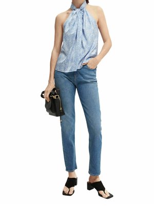 Top halter azul claro con patrón texturizado, combinado con jeans ajustados azules y sandalias negras de tacón bloque. Detalle de bolso negro.