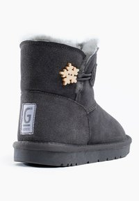 Botas de ante gris con forro de piel de oveja, suela de goma y adorno decorativo de copo de nieve de madera. Presenta una costura cosida y una etiqueta de marca.