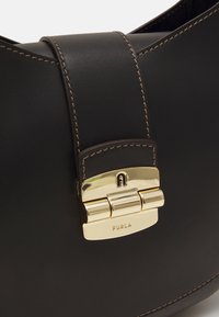 Tmavě hnědá kožená kabelka s béžovým prošíváním a zlatým zapínáním s rytinou "FURLA" a malým logem "A".