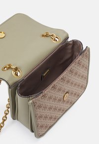 Zielona torebka z ekologicznej skóry z złotymi akcentami, z brązową, wzorzystą klapą i dwiema przegrodami, zamykana na zatrzask.