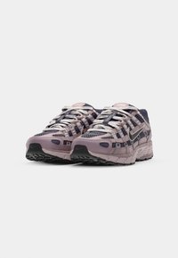 Baskets Nike en violet clair et marine foncé avec des superpositions en mesh, des semelles texturées, des lacets multicolores et une marque sur la languette.