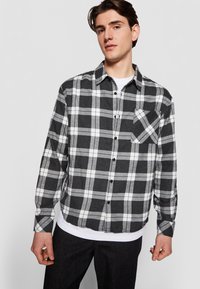 Sort og hvid ternet flannel-skjorte, knap-op stil med en brystlomme, der har kontrasterende farver og en afslappet pasform.
