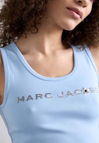 Svijetloplavi majica bez rukava s okruglim izrezom i sjajnim detaljima od rhinestonesa koji ispisuju "MARC JACOBS" uz dodatak cvijeta.