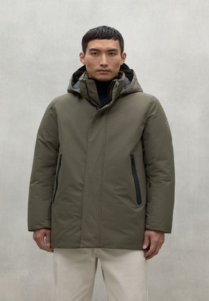 Chaqueta aislante verde oliva con capucha, que cuenta con dos bolsillos frontales con cremallera y un acabado matte suave. Diseño simple y moderno.