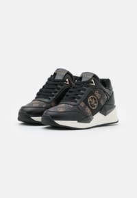 Svarta sneakers i läder och syntetmaterial, med ett mönstrat ovandel, guldaccenter och en kraftig vit sula.