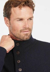 Marineblauer gestrickter Pullover mit hohem Kragen, der eine gerippte Textur aufweist und vier braune Knöpfe entlang der Vorderblende hat.