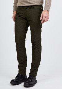 Tummanvihreät mokkalahkeet, joissa on kapea leikkaus. Mukana viisi taskua ja vyölenkit, yhdistetty mustiin nauhakorkoihin.