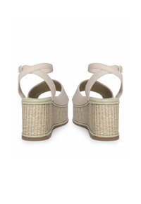 Beige wedge sandalen met een geweven jute zool, verstelbare achterband en kruislings lederen banden bij de enkel. Gladde textuur, afgeronde randen.