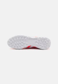 Red and white athletic shoe sole featuring a textured rubber pattern, with "PREDATOR" branding embossed on a white background.
