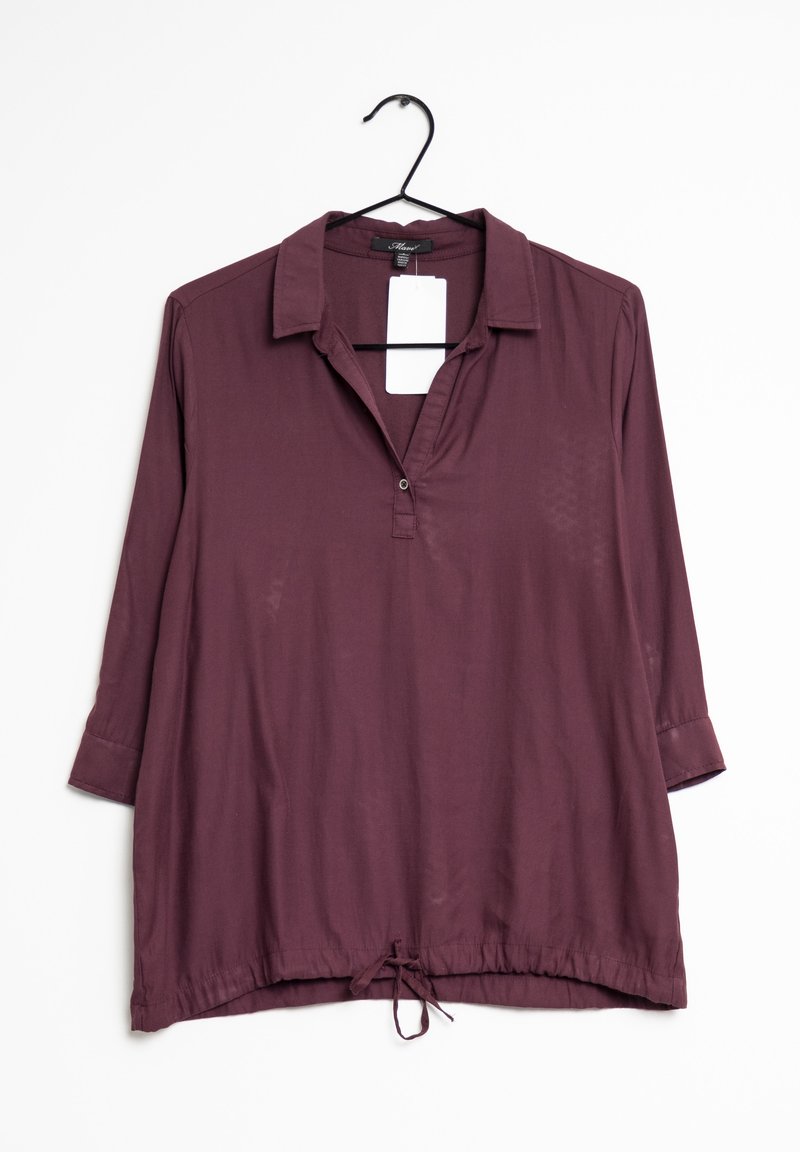 Blouse prune à manches longues avec col, ouverture partielle boutonnée à l'avant, ourlet avec cordon de serrage et étiquette, suspendue sur un cintre noir sur fond blanc.