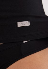 Czarna bawełniana odzież o miękkiej fakturze, z widoczną metką "intimissimi Natural", prezentująca staranne szwy i bezszwowy design.