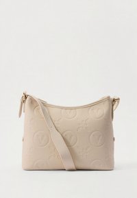 Beige crossbody bag made of textured faux leather, featuring embossed floral and logo patterns, with an adjustable strap and zip closure.