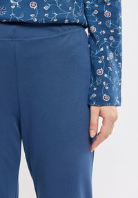 Pantalons en tissu doux bleu marine avec une texture lisse, dotés d'une taille élastique et d'une coupe légèrement fuselée.