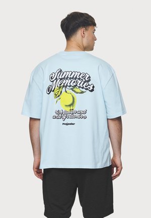 Light blue short-sleeve t-shirt featuring a graphic design of a lemon and text on the back. Soft cotton material, relaxed fit.