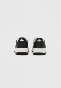 Adidași negri din piele cu accente și logo albe, vârf rotund, guler căptușit și talpă de cauciuc texturată.