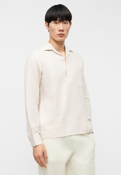 Ελαφρώς μπεζ πουκάμισο με μακριά μανίκια, με μερικό κουμπωτό πέτο και πλαϊνή τσέπη, με άνετη εφαρμογή και υφή από λινό ύφασμα.