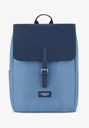 Kék hátizsák sima, enyhén fényes felülettel. A jellemzői közé tartozik a sötétkék fedél, elülső csatbezárás és egy márka címke az alján.