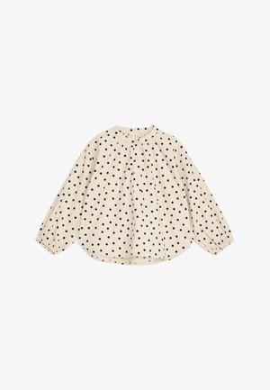 Blouse crème à manches longues avec des pois noirs, col rond, boutonnage devant et poignets élastiqués, présentée à plat sur fond blanc.