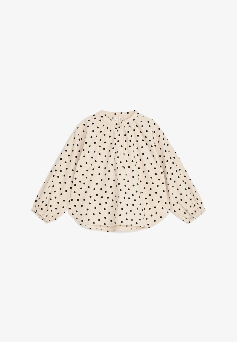 Blouse crème à manches longues avec des pois noirs, col rond, boutonnage devant et poignets élastiqués, présentée à plat sur fond blanc.