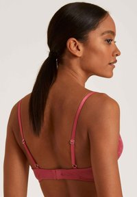 Roze beha met een zachte textuur, verstelbare bandjes en een haak-en-oog sluiting op de rug. Voorzien van een delicate kantoverlay.