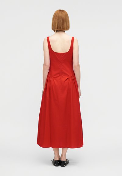 Κόκκινο φόρεμα χωρίς μανίκια με στρογγυλή πλάτη, λεπτομέρεια ραβδώματος στη μέση και φαρδιά φούστα. Κατασκευασμένο από ελαφρύ βαμβακερό ύφασμα.